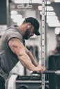 Strong young bearded tired man with eyes closed leaning on fitness exercise equipment during training pause for mind