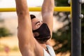 Strong young latin man doing calisthenics with mask