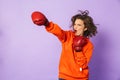 Strong young woman boxer posing isolated over purple background wall wearing boxing gloves