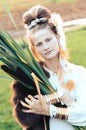 Strong young woman with a bulrush grass reed on rural field background at sunset