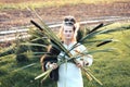 Strong young woman with a bulrush grass reed on rural field background at sunset