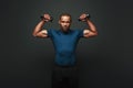 Stronger and faster. Dark skinned sportsman working out with dumbbells over dark background Royalty Free Stock Photo