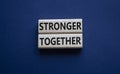 Stronger together symbol. Wooden blocks with words Stronger together. Beautiful deep blue background. Stronger together concept.