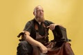 Comic portrait of muscular bearded bald man, blacksmith in leather apron or uniform isolated on yellow studio background