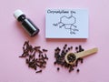 Structural chemical formula of caryophyllene, clove essential oil glass bottle, clove grains and peppercorns on pink background Royalty Free Stock Photo