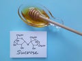 Structural chemical formula of sucrose with a bowl of honey. Sucrose occurs naturally in honey, alternative to refined sugar