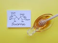 Structural chemical formula of sucrose with a bowl of honey. Sucrose occurs naturally in honey, alternative to refined sugar