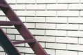 Part of the stairs red metal ladder leading up against of a white brick wall Royalty Free Stock Photo