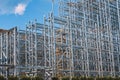 Structure of a new steel frame of a building on an industrial construction site. Against the background of a blue sky with clouds Royalty Free Stock Photo