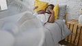 Struggling with the heat, a beautiful african american woman with braids finds comfort in her cozy bedroom, relaxing on her bed