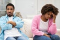 Stubborn black couple sit on couch side by side Royalty Free Stock Photo