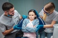 Stubborn girl sit in ddental cair in room. Dentists look at her worried. They touch and talk to her. on green Royalty Free Stock Photo