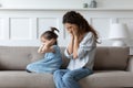 Stubborn spoiled little girl covering ears, ignoring hopeless upset mother