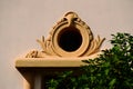 stucco house elevation detail with decorative small round window molding. lush fig tree in front Royalty Free Stock Photo