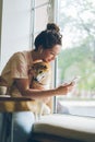 Student using smartphone enjoying music in earphones stroking dog in cafe Royalty Free Stock Photo