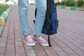 A student with a backpack goes to study. Return to school, university. Dressed in blue jeans and pink sneakers