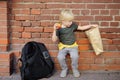 Student with big backpack and lanch bag sat down to eat his lanch near the school building. School meals Royalty Free Stock Photo
