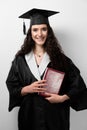 Student with book in graduation robe and cap ready to finish college. Future leader of science. Academician young woman