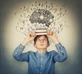 Student boy looks up curious as holds two books on his head, feeling overwhelmed and exhausted of constant learning. Cogwheel