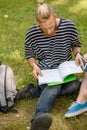 Student boy sitting on grass studying.