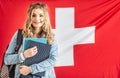 Student in braces smiles holding study material in from of flag of Switzerland