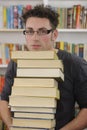 Student carrying stack of books in library Royalty Free Stock Photo