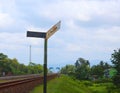 Old rusty railway sign stands by train tracks Royalty Free Stock Photo
