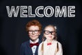 Student children little boy and girl against chalkboard background with welcome inscription