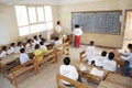 Student in classroom writing Arabic on blackboard