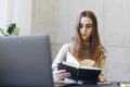 Woman concentrated on studying in front of laptop. Girl making notes watching educational webinar online. Distant courses for Royalty Free Stock Photo