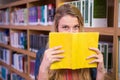 Student covering face with book in library