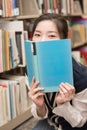 Student covering mouth with book