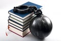 Student debt concept with a stack of books next to a ball and chain symbolizing the burden tuition costs represent isolated on