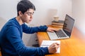 Student doing homework at his desk with laptop Royalty Free Stock Photo