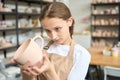 Student examines an unfired homemade clay cup with a handle