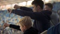 Student fans and little boy booing sport game at stadium, watching junior match