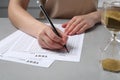 Student filling answer sheet at light grey table, closeup. Passing exam Royalty Free Stock Photo