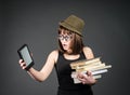 Student in funny glasses with old books in one hand and e-reader in another on grey background. Nerd girl is comparing Royalty Free Stock Photo