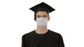 Student in gaduation gown and face mask stumbling on white background. Royalty Free Stock Photo