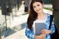 Student girl with books and backpack standing near modern facade Royalty Free Stock Photo