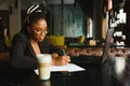 Student girl browsing Internet, using free wi-fi at cafe. African freelancer thinking on ideas for her blog, using laptop at co- Royalty Free Stock Photo