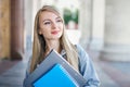 student girl freshman stands on the background of an old white university building with ancient columns and smiles