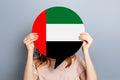 student girl holds blank white speech bubble with UAE flag isolated over grey studio background