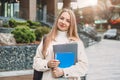 student girl holds folders notebooks books in hands smiles against the background of a modern university building Royalty Free Stock Photo