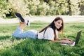 Student girl with laptop outdoors. Smiling woman lying on the grass with a computer, surfing the Internet or preparing for exams. Royalty Free Stock Photo