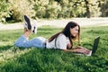 Student girl with laptop outdoors. Smiling woman lying on the grass with a computer, surfing the Internet or preparing for exams. Royalty Free Stock Photo