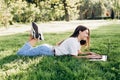 Student girl with laptop outdoors. Smiling woman lying on the grass with a computer, surfing the Internet or preparing for exams. Royalty Free Stock Photo