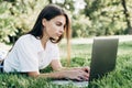 Student girl with laptop outdoors. woman lying on the grass with a computer, surfing the Internet or preparing for exams. Royalty Free Stock Photo