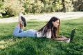 Student girl with laptop outdoors. woman lying on the grass with a computer, surfing the Internet or preparing for exams. Royalty Free Stock Photo