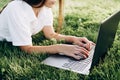 Student girl with laptop outdoors. woman lying on the grass with a computer, surfing the Internet or preparing for exams. Royalty Free Stock Photo